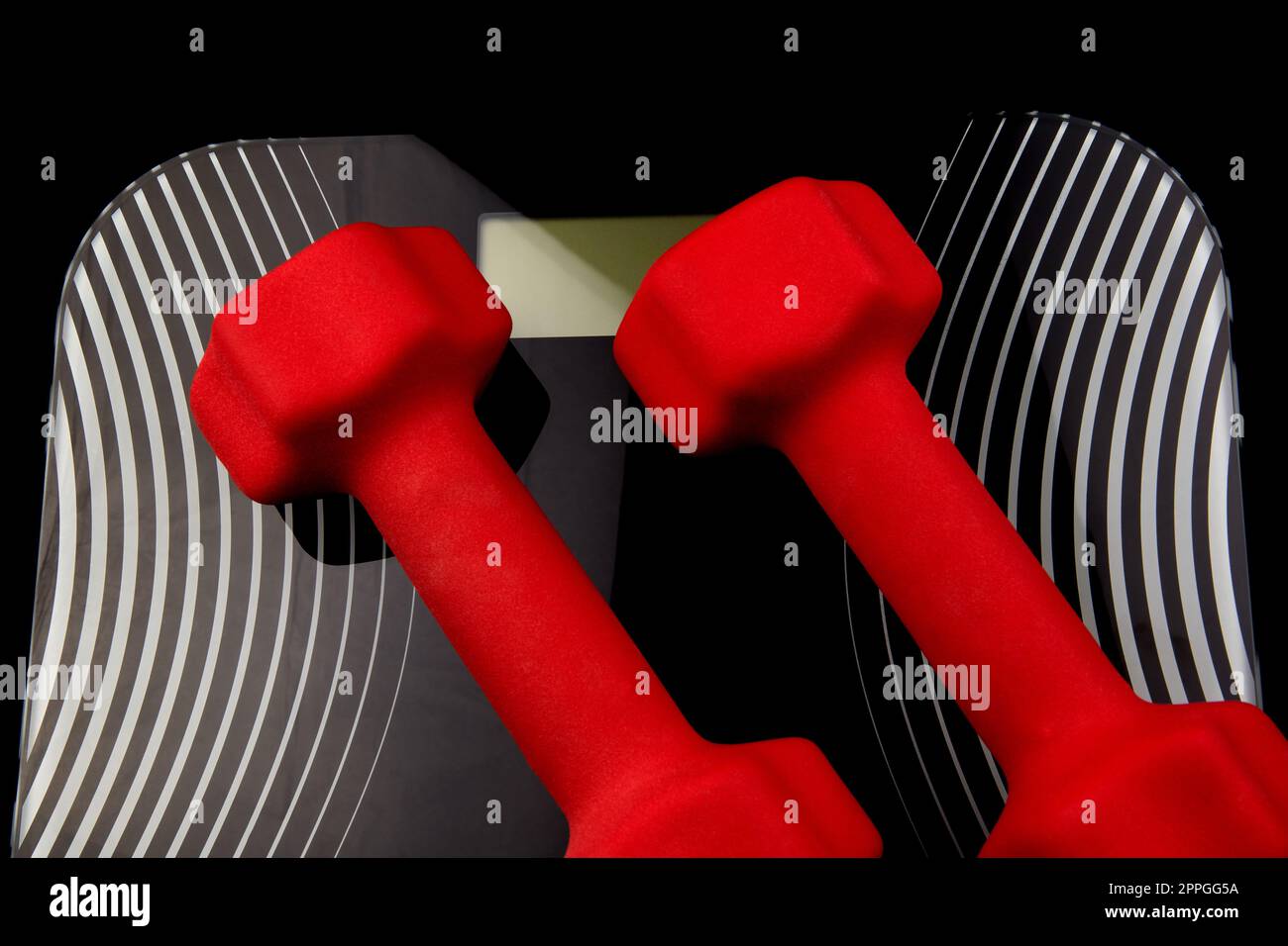 Red dumb bells on an electronic weighing scales device Stock Photo