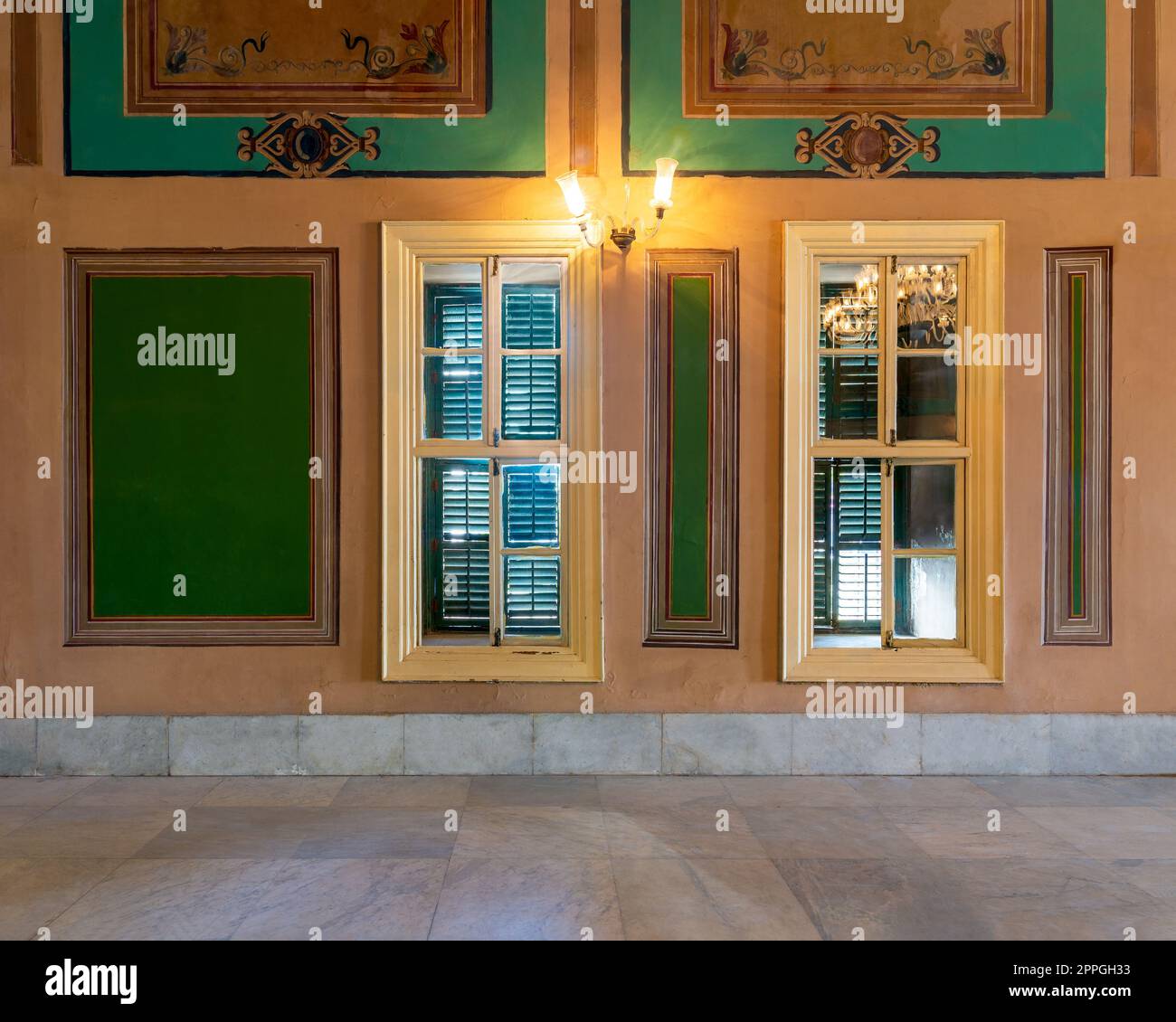 Wooden window with green shutters mediating elegant rectangular green frames on orange wall Stock Photo