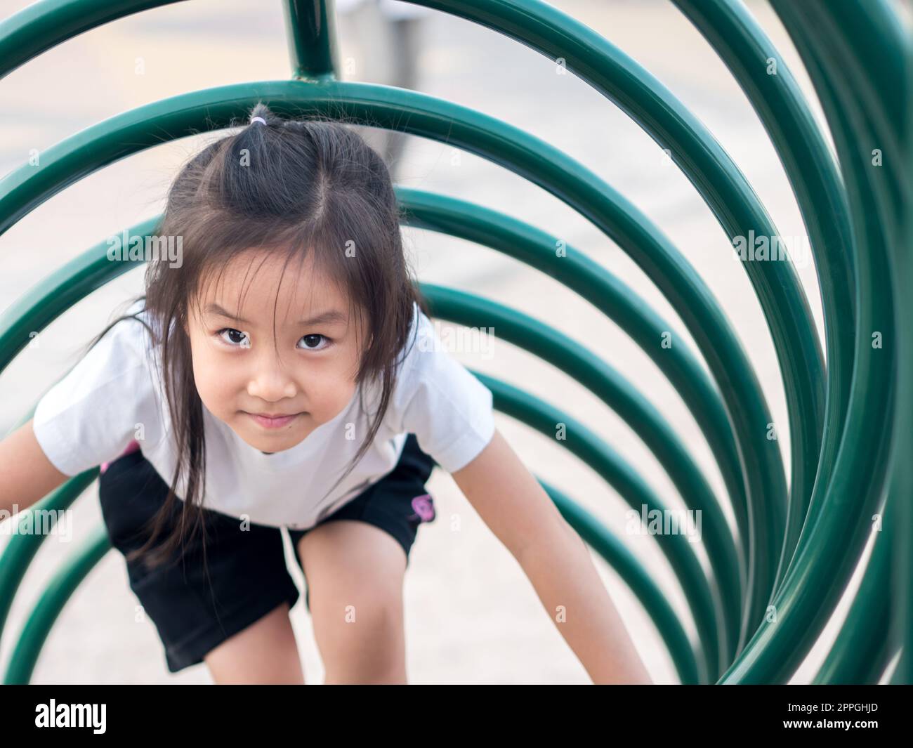 Happy kid, asian baby child playing on playground, climb the playground equipment, circle shape, white T shirt Stock Photo