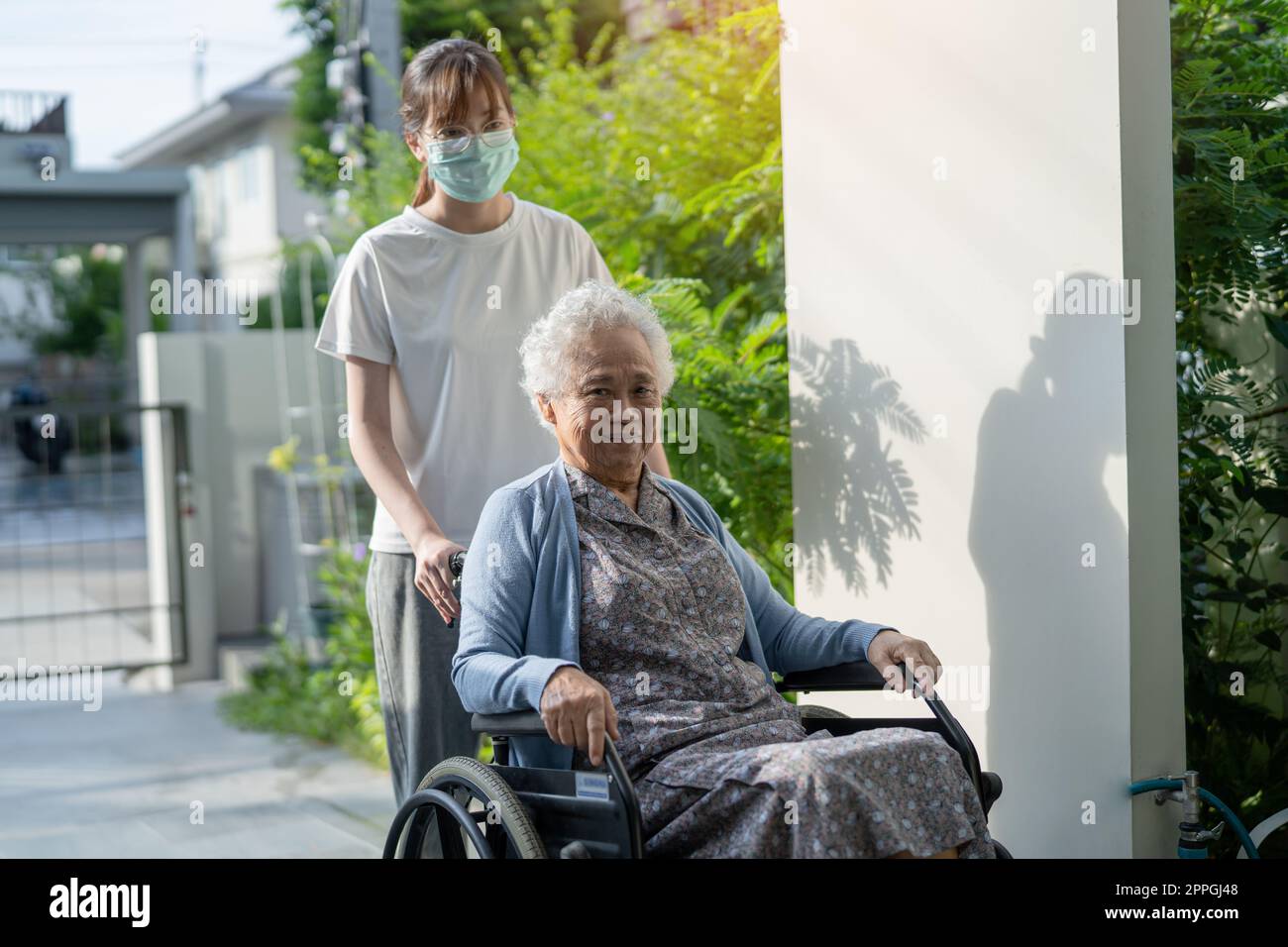Caregiver help and care Asian senior or elderly old lady woman patient sitting on wheelchair to ramp in nursing hospital, healthy strong medical concept. Stock Photo