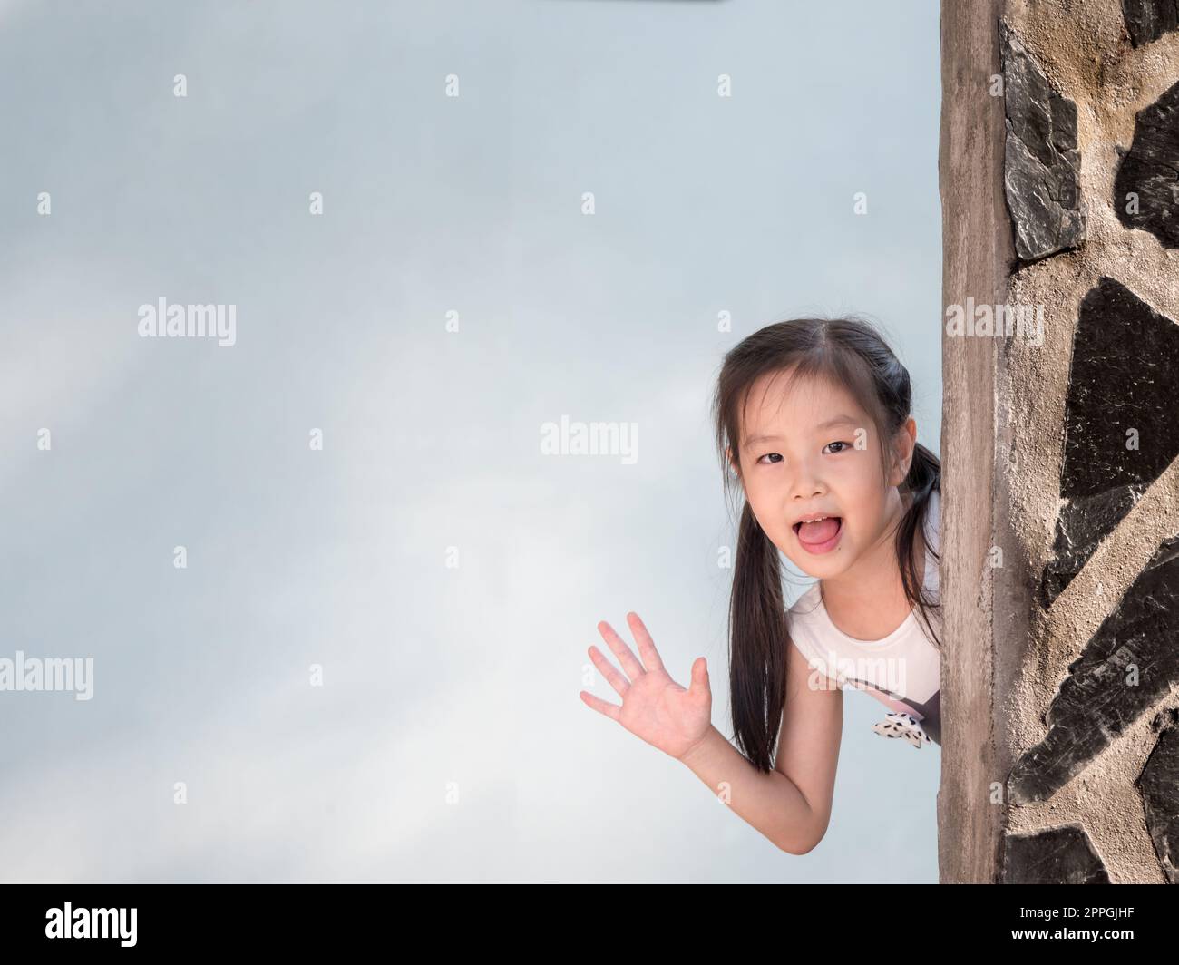 Asian girl hiding behind the wall, peekaboo action Stock Photo Alamy