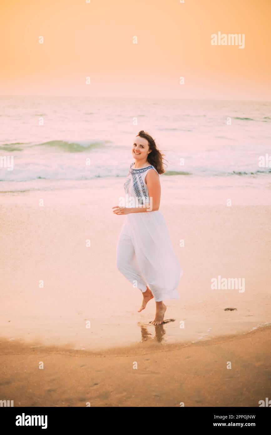 Goa, India. Young Caucasian Woman In White Dress Walking Along Seashore,  Looking At Camera And Smiling In Summer Sunlight Stock Photo - Alamy