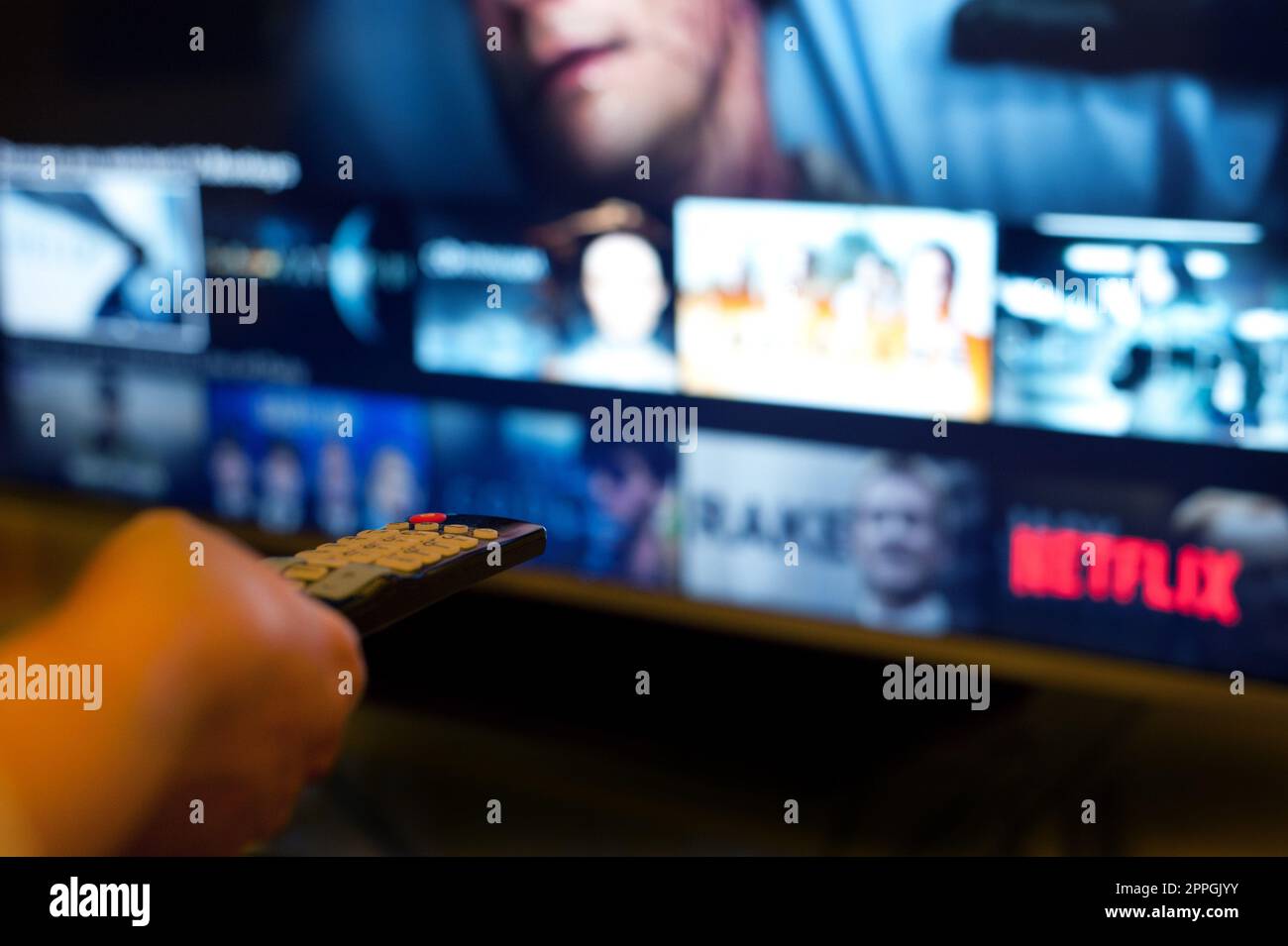 pointing a remote to TV, choosing program to watch on Netflix Stock Photo