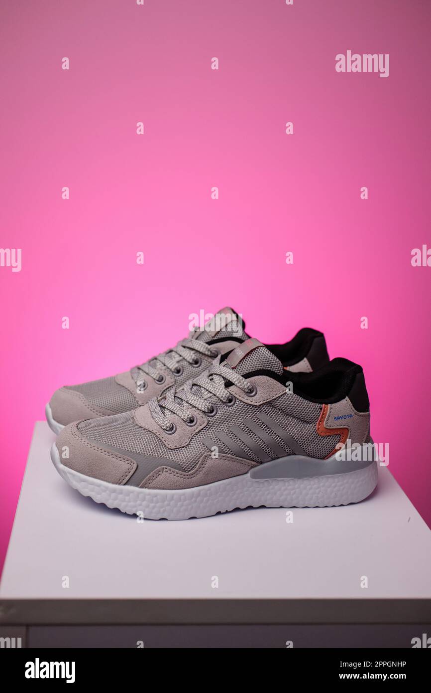 Pair of sports shoes standing on white podium on pink background. Stock Photo