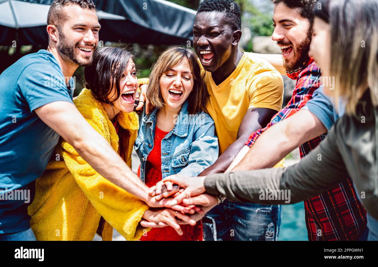Young diverse friends stacking hands on positive union mood - Multi racial unity culture among students having fun together - Life style friendship co Stock Photo