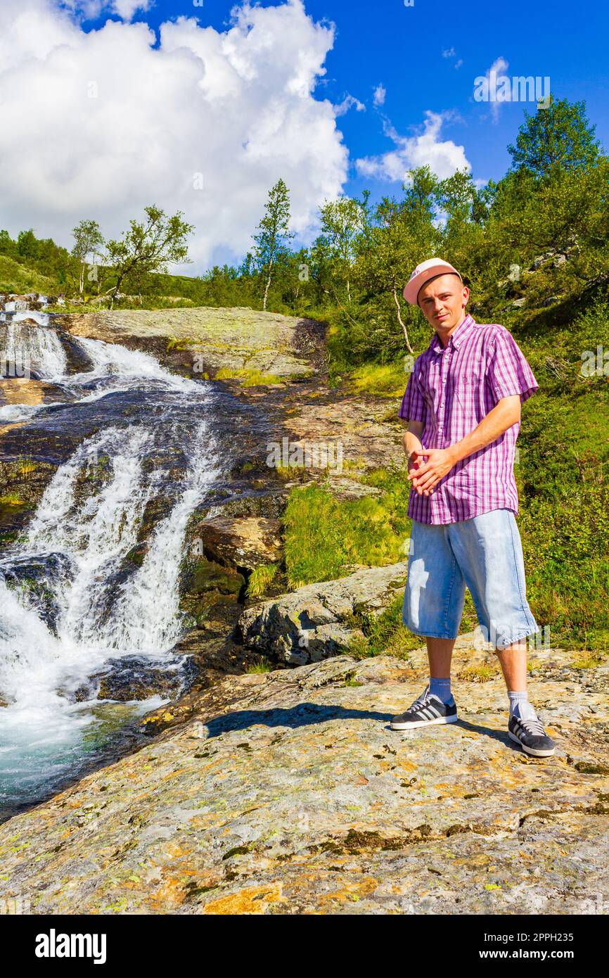 Man tourist in front of beautiful waterfall river Vang Norway. Stock Photo