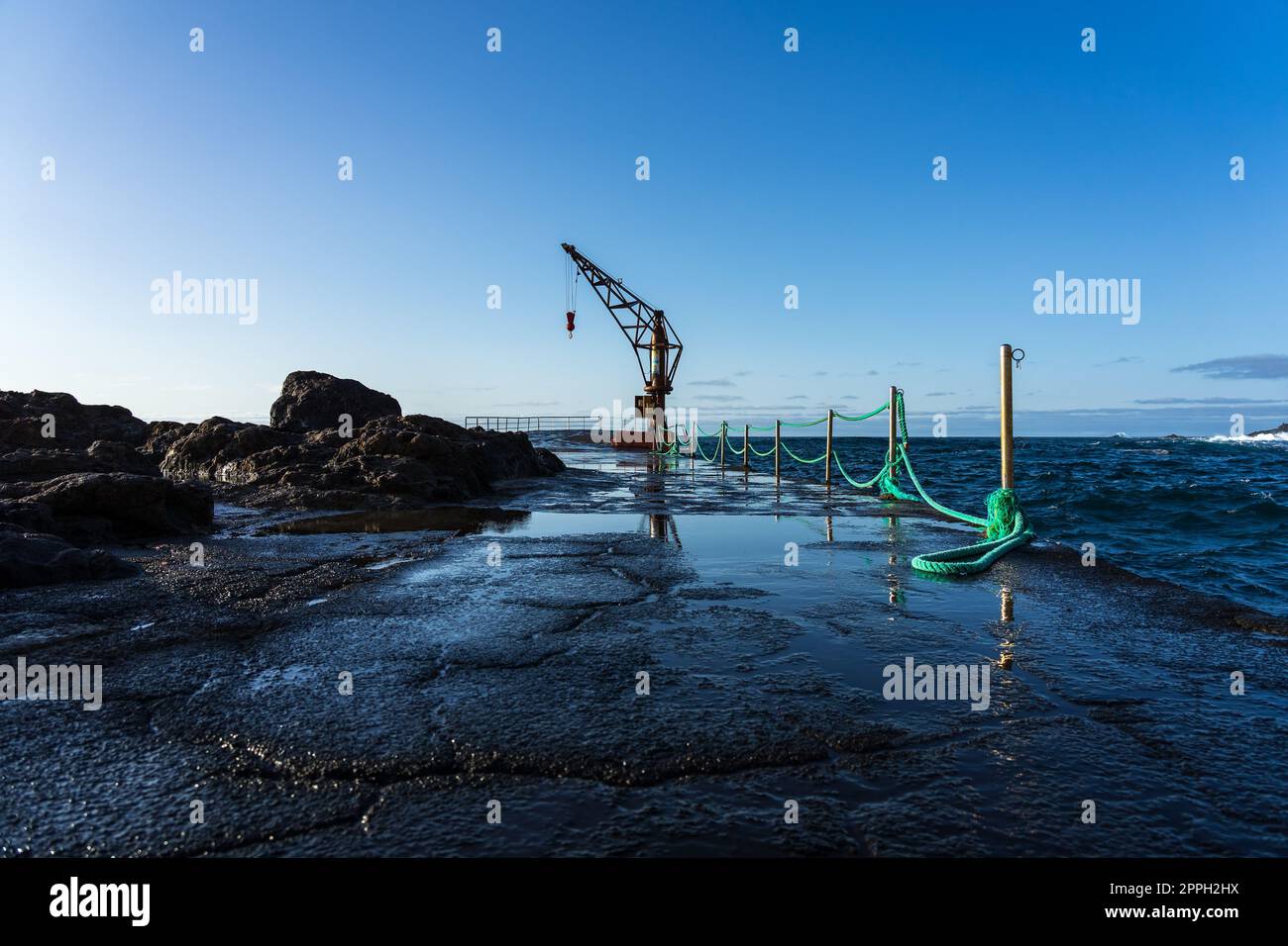 Berth with a crane on the north coast of the Atlantic Ocean, the village of El Pris. Tenerife. Canary Islands. Spain. Stock Photo