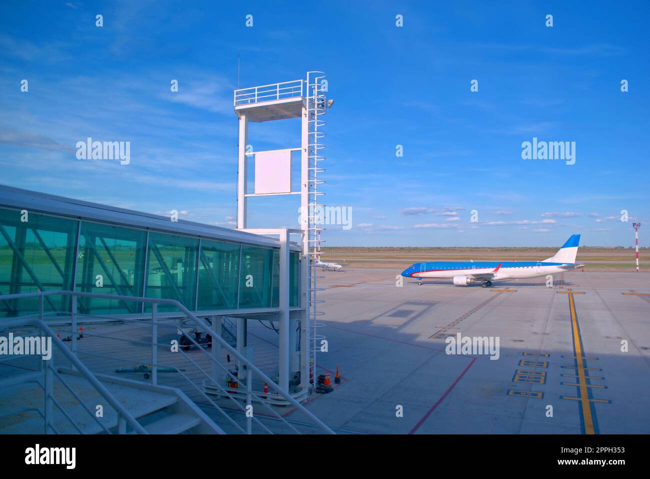 Commercial jet plane taxiing by the boarding bridge of an airport. Stock Photo