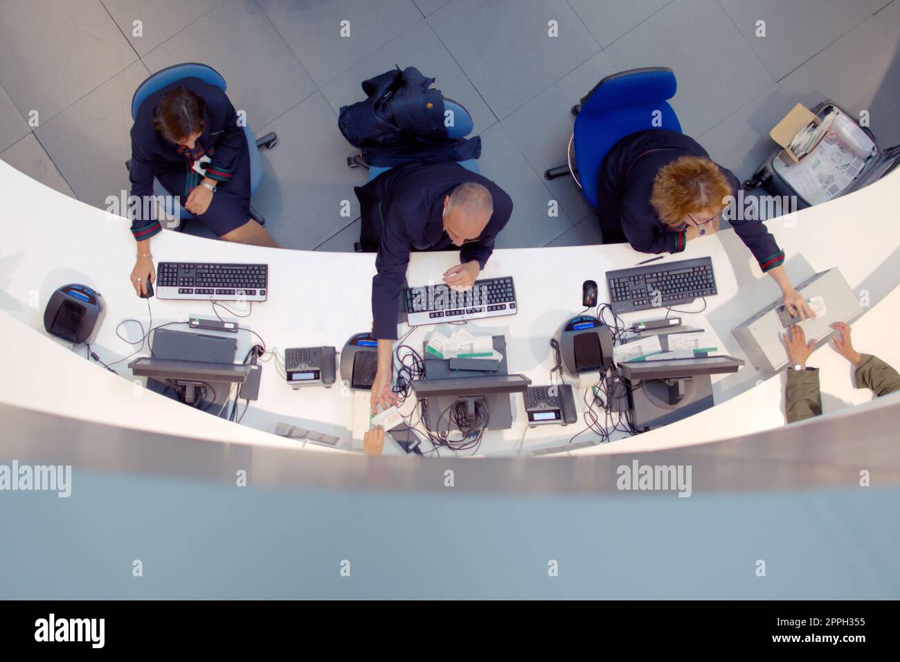 Three customer service agents working at a help desk at the airport. Stock Photo