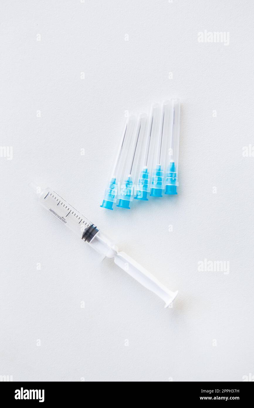 There is a syringe and injection needles on a white table. The concept of vaccination and health. View from above. Stock Photo