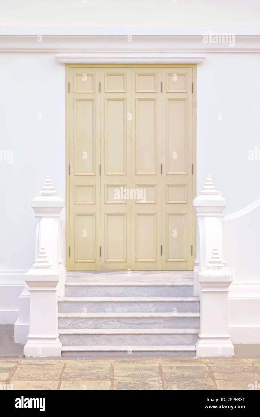 Muted beige painted wooden door on a white wall. Stock Photo