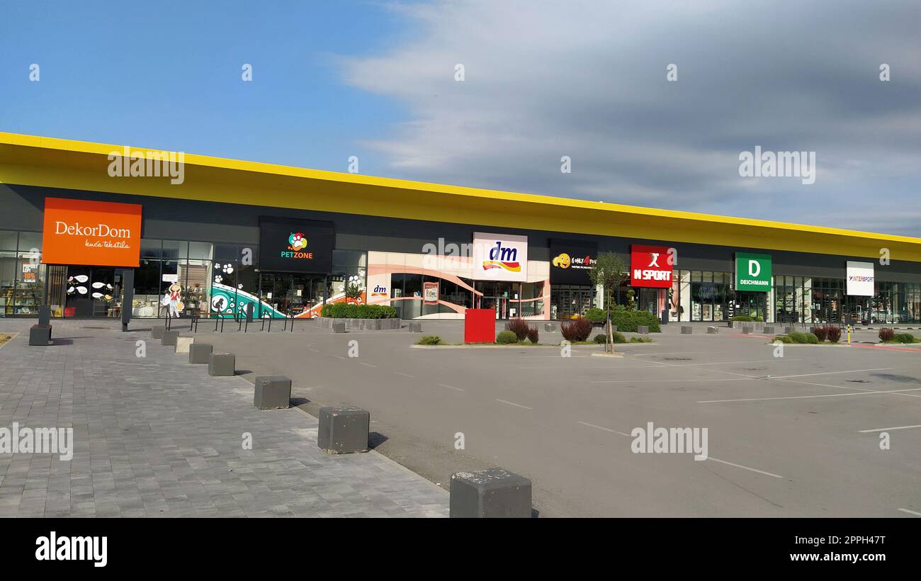 Stop shop shopping center, Sremska Mitrovica, Serbia, June 06, 2022. Square with open shops dm, intersport, dekordom, ccc, lc waikiki. People, parking and pavement. Sunny summer day Stock Photo