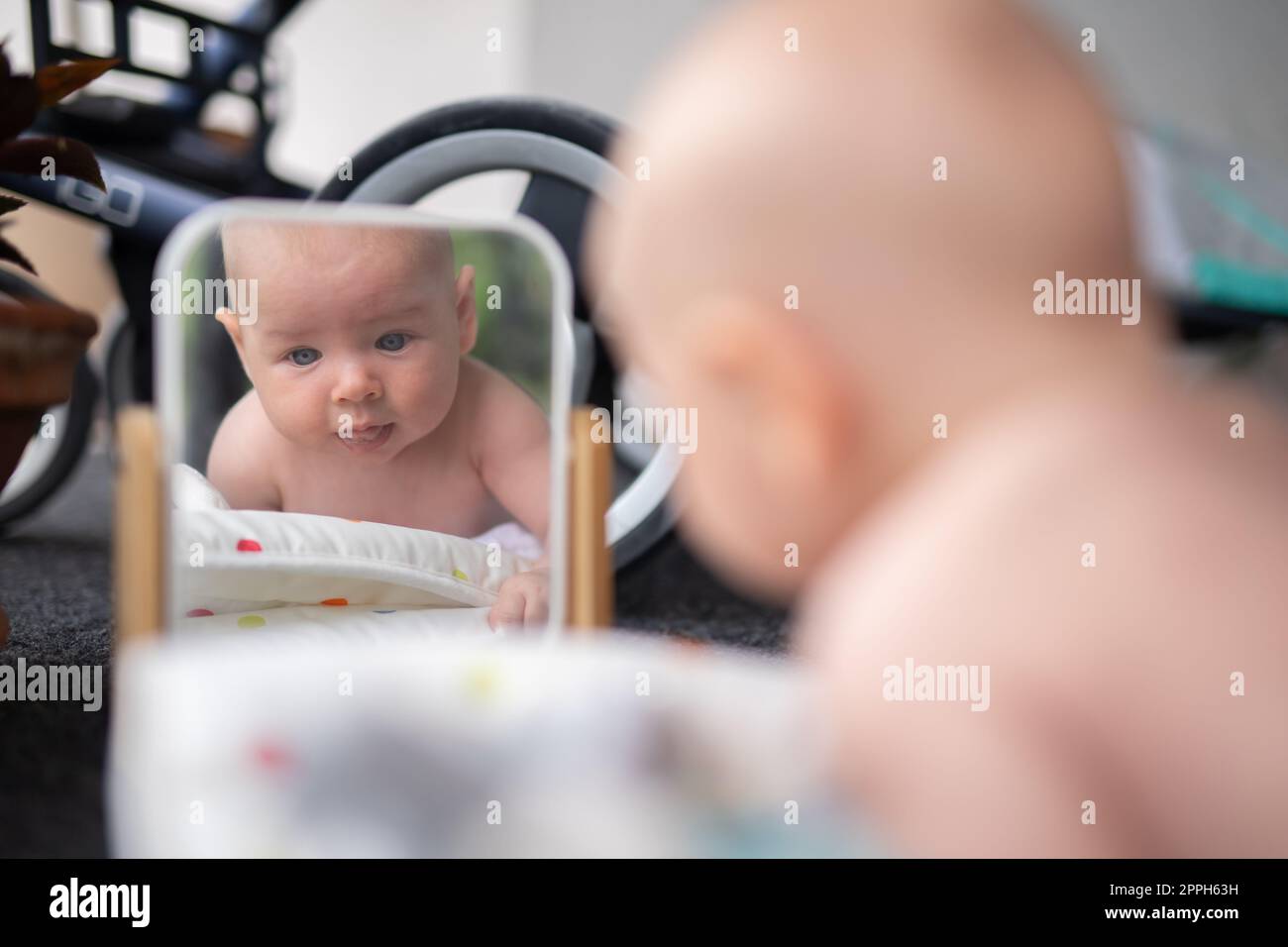 Beautiful shot of a cute baby boy looking at his reflection in the mirror. Stock Photo