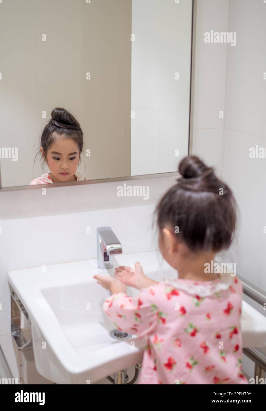 Asian little kid girl wash her hand in the toilet Stock Photo