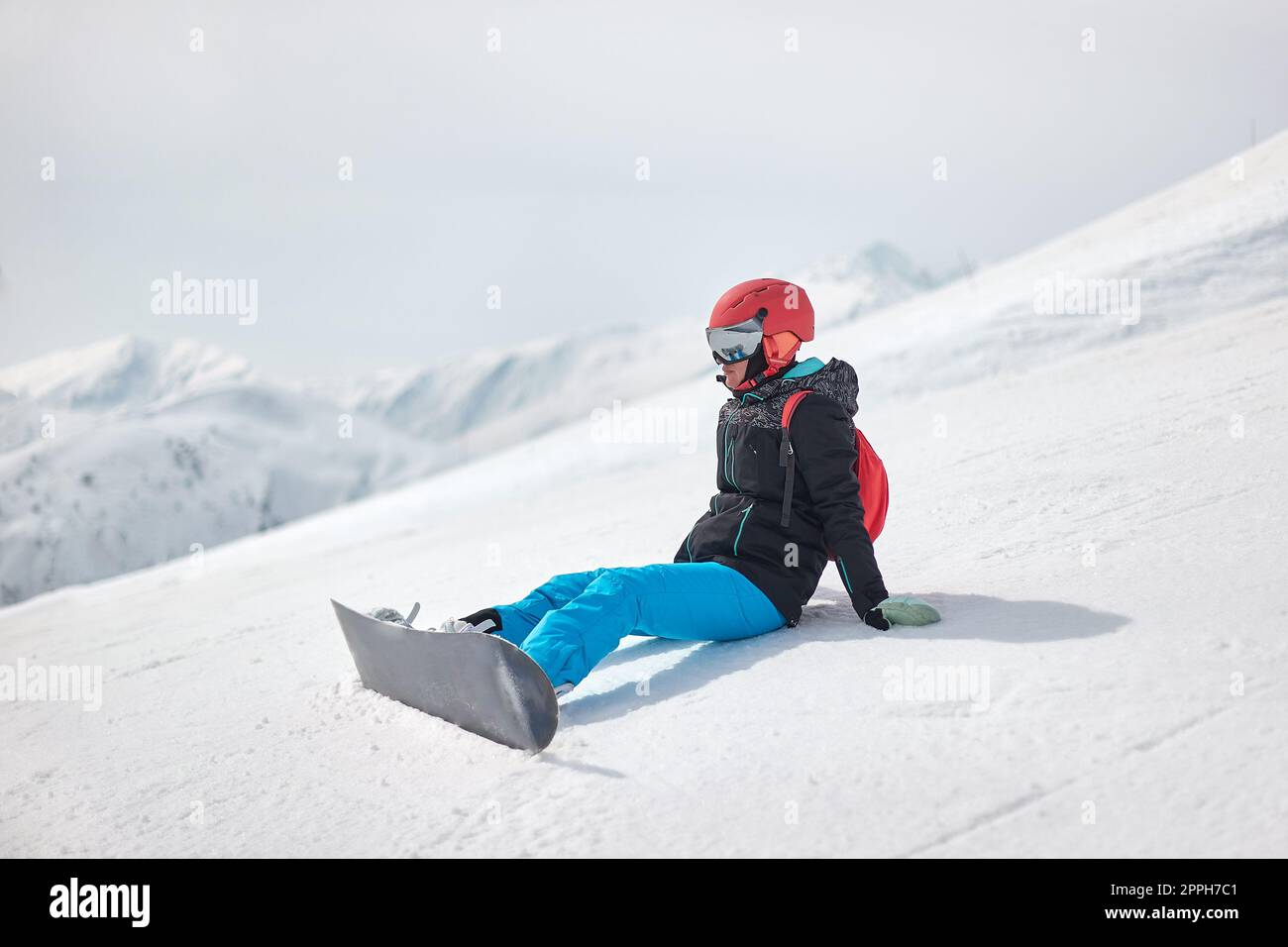 Snowboarder sitting in the white snow Stock Photo