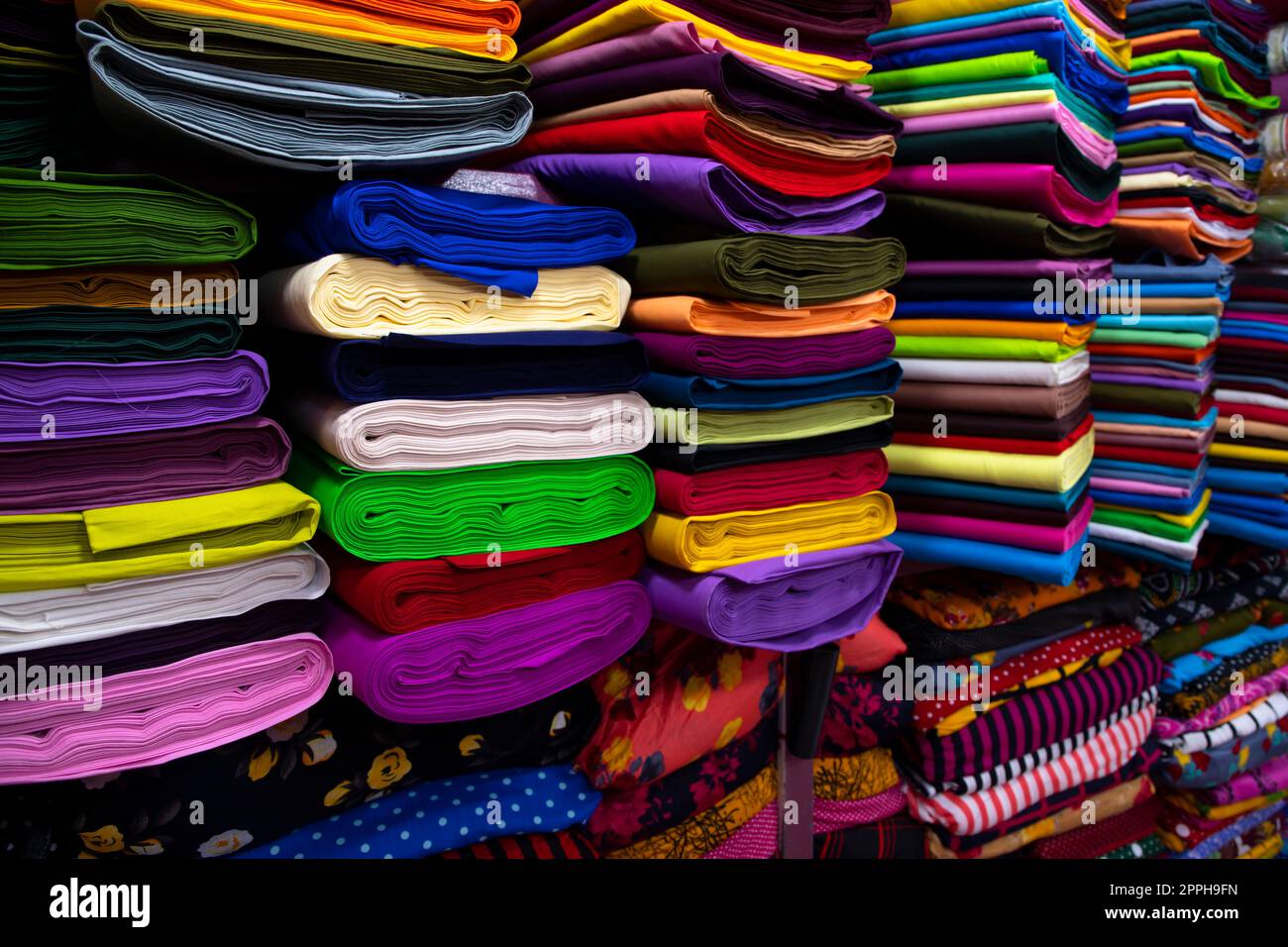 Artistic variety shade tone colors Textile Fabrics stacked on retail Shop Shelf to sale Stock Photo
