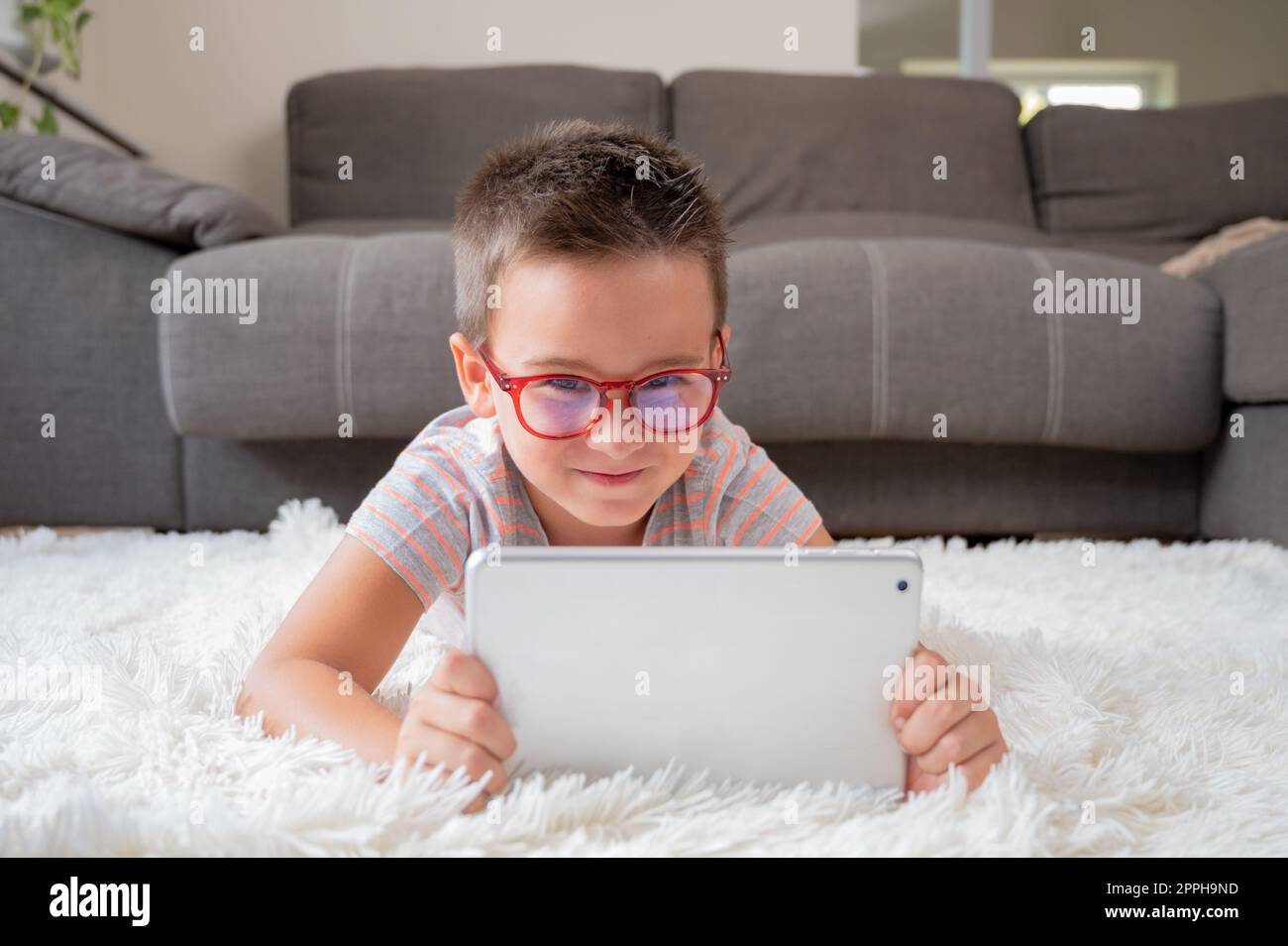 Adorable little boy using a digital tablet on the floor at home Stock ...