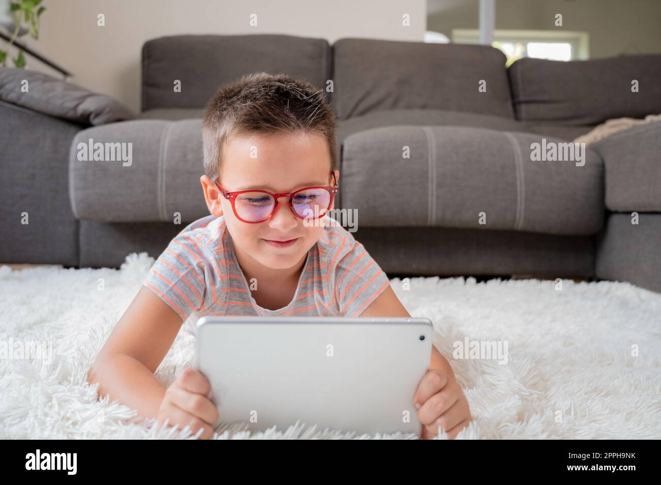 Adorable little boy using a digital tablet on the floor at home Stock ...