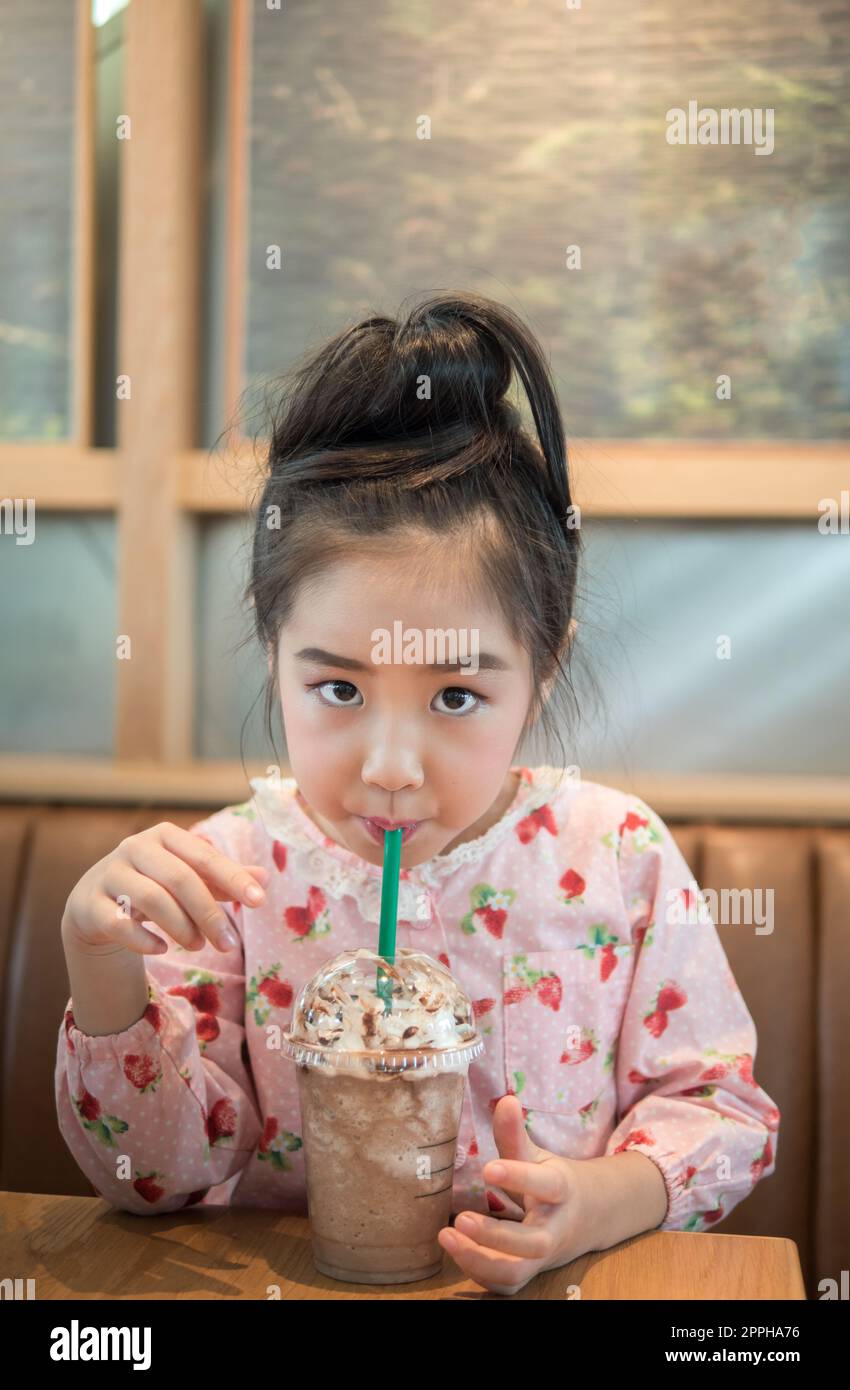 Beautiful asian girl drinking iced chocolate in the cafe, use  a straw Stock Photo