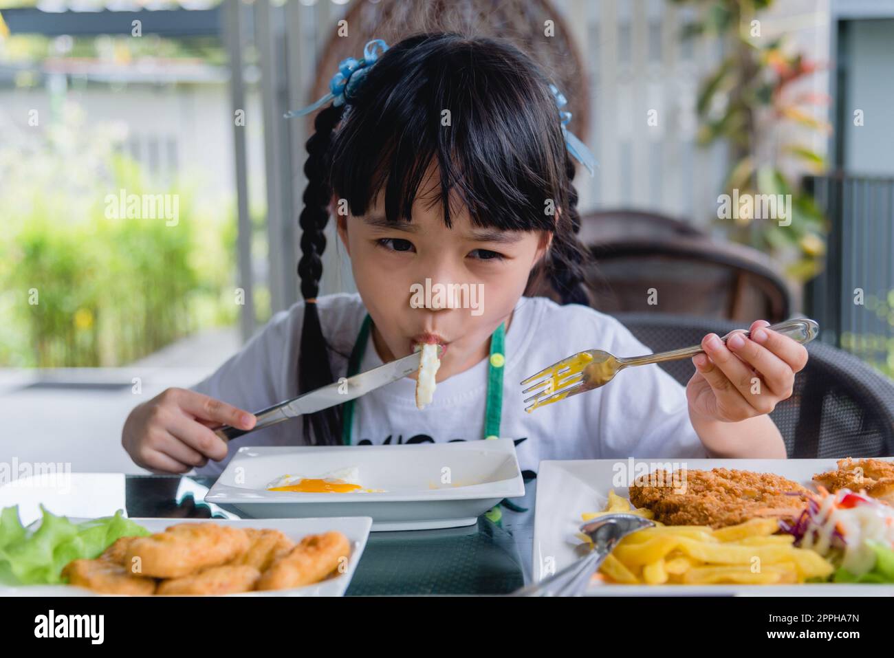little girl asian eat fried egg on dish at table Stock Photo Alamy