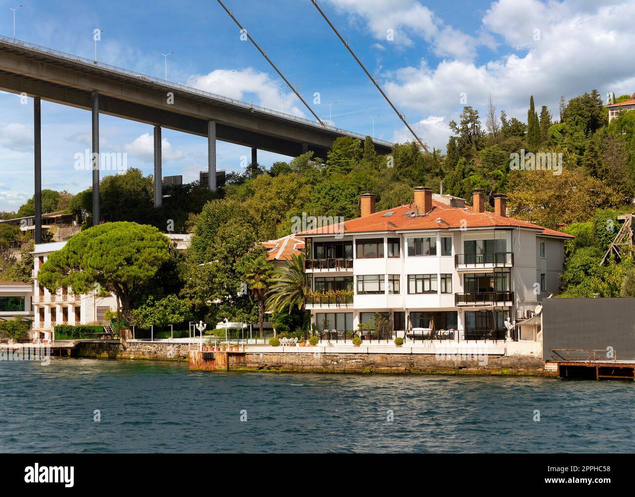 Traditional waterfront house, under Bosphorus bridge, and green hill with  dense trees, Istanbul, Turkey Stock Photo - Alamy