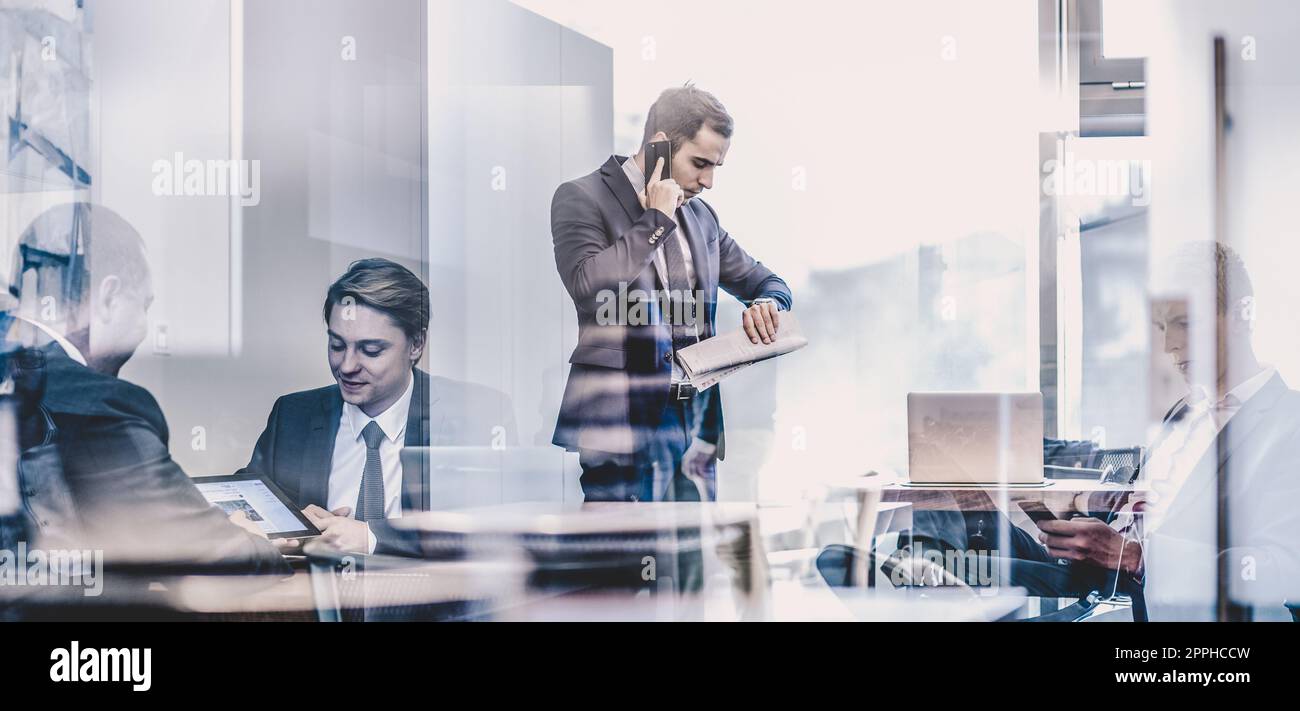 Businessman talking on a mobile phone on corporate office. Stock Photo