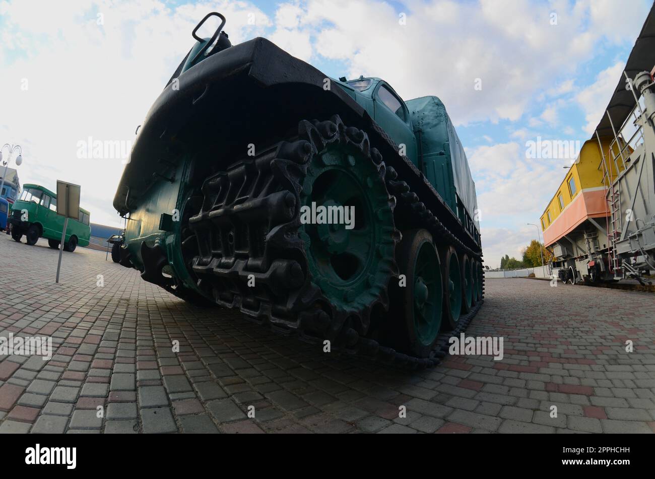 Photo of a Russian green armored car on a caterpillar track among the railway trains. Strong distortion from the fisheye lens Stock Photo