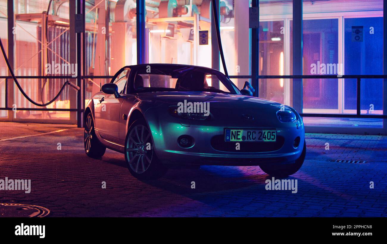 Mazda MX5, Miata, NC at night in front of a red and blue illuminated carwash Stock Photo