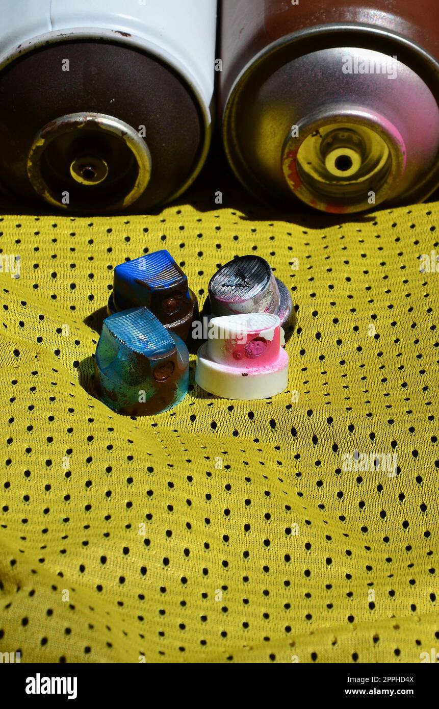Several caps for used aerosol paint sprayers lie on the sports shirt of a basketball player made of polyester fabric. The concept of youth street art, active sports and eventful lifestyle Stock Photo