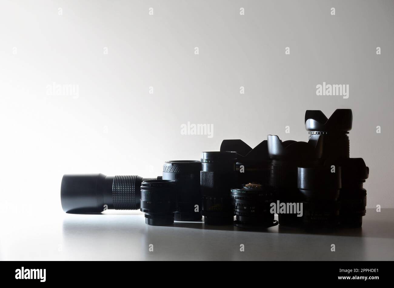 Many different professional lenses for SLR camera lies on a colorless desk Stock Photo