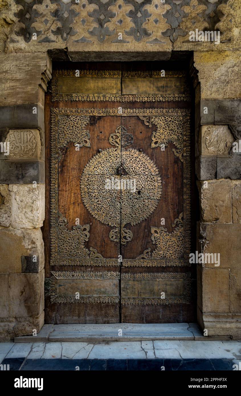An aged door at the main yard of Al-Sultan Al-Zahir Barquq mosque. Al-Moez Street, Old Cairo, Egypt Stock Photo