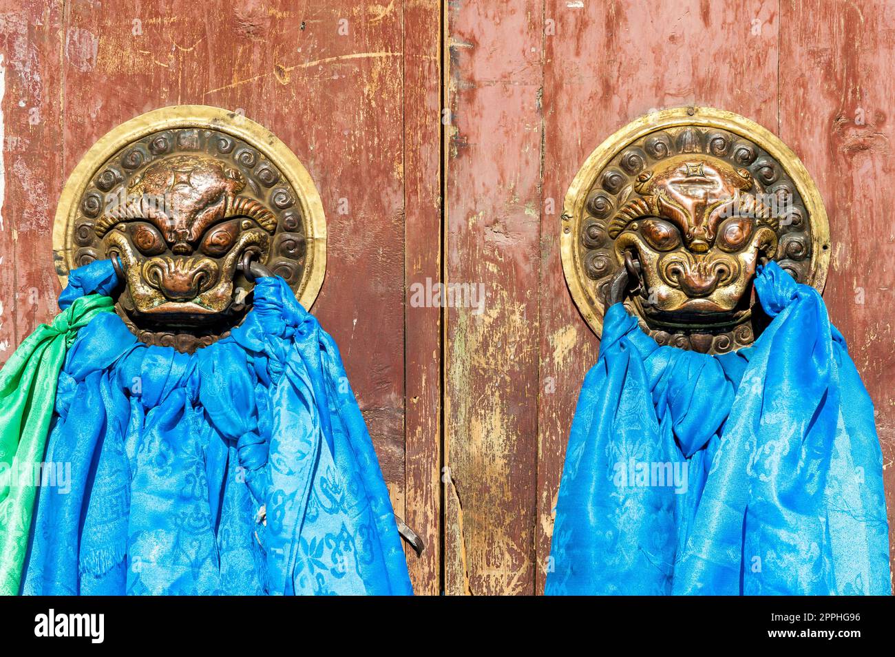 Two decorated door knockers draped with prayer cloths at a gate to a Buddhist monastery in Karakorum, the former capital of Mongolia, Central Asia Stock Photo