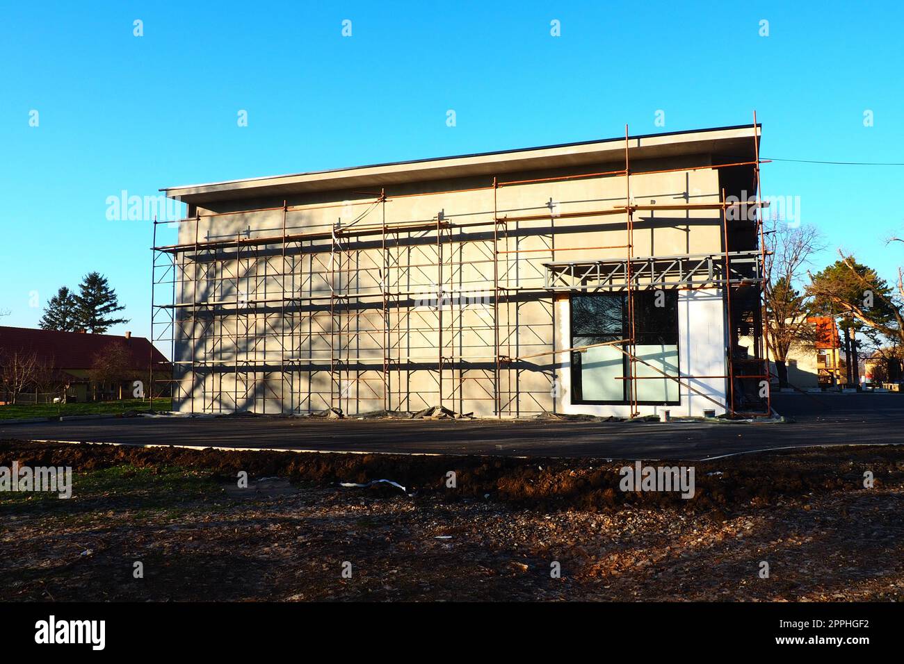 Scaffolding on a new one-story house. Facade works. Building bussiness. Low-rise private building. Plastering the wall of a building. Shop building. Metal production structures. Stock Photo