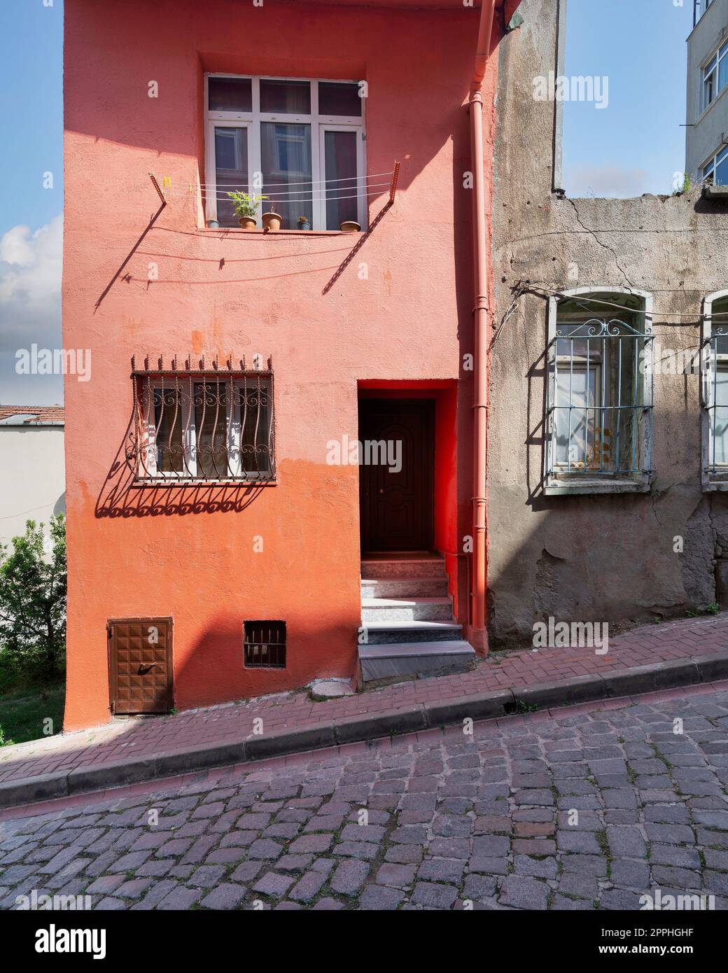 Old house painted in orange, and wrought iron windows, at a cobblestone street, Balat district, Istanbul, Turkey Stock Photo