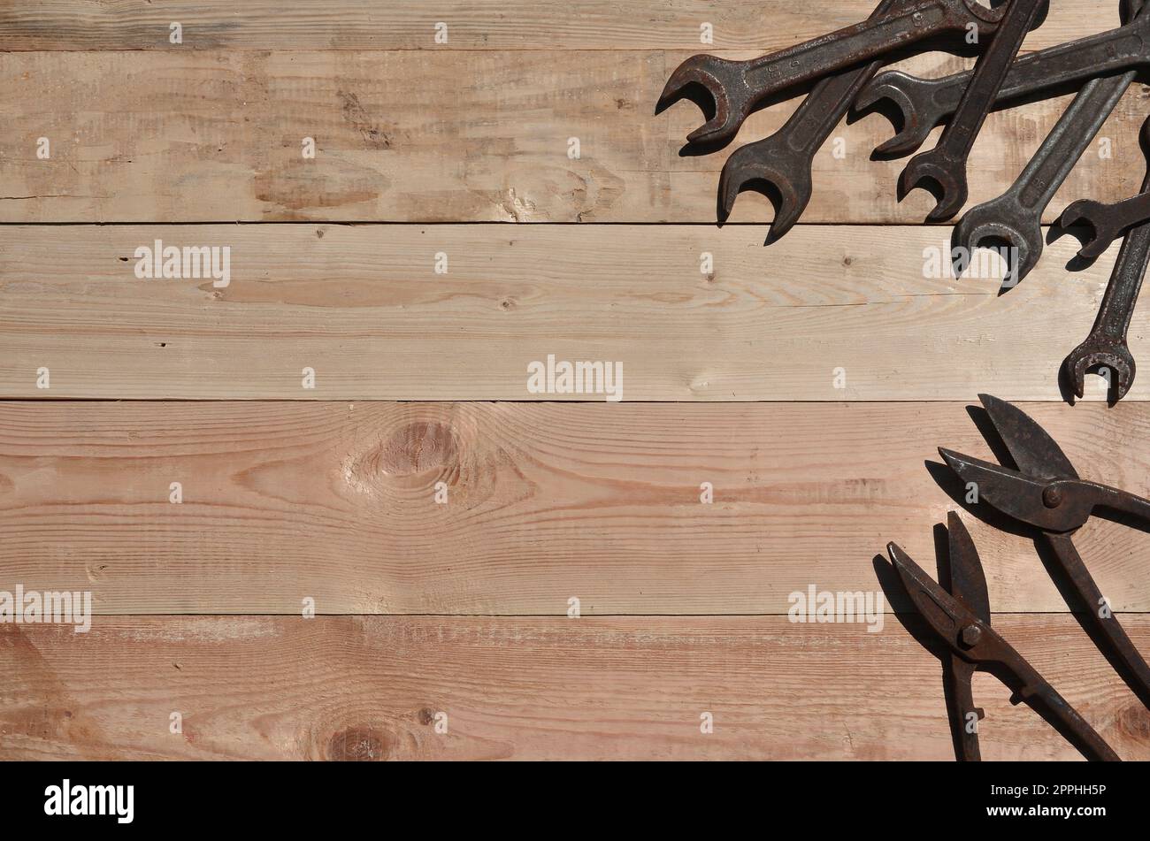 A few rusty spanners and scissors for metal lies on a wooden table in a workshop Stock Photo