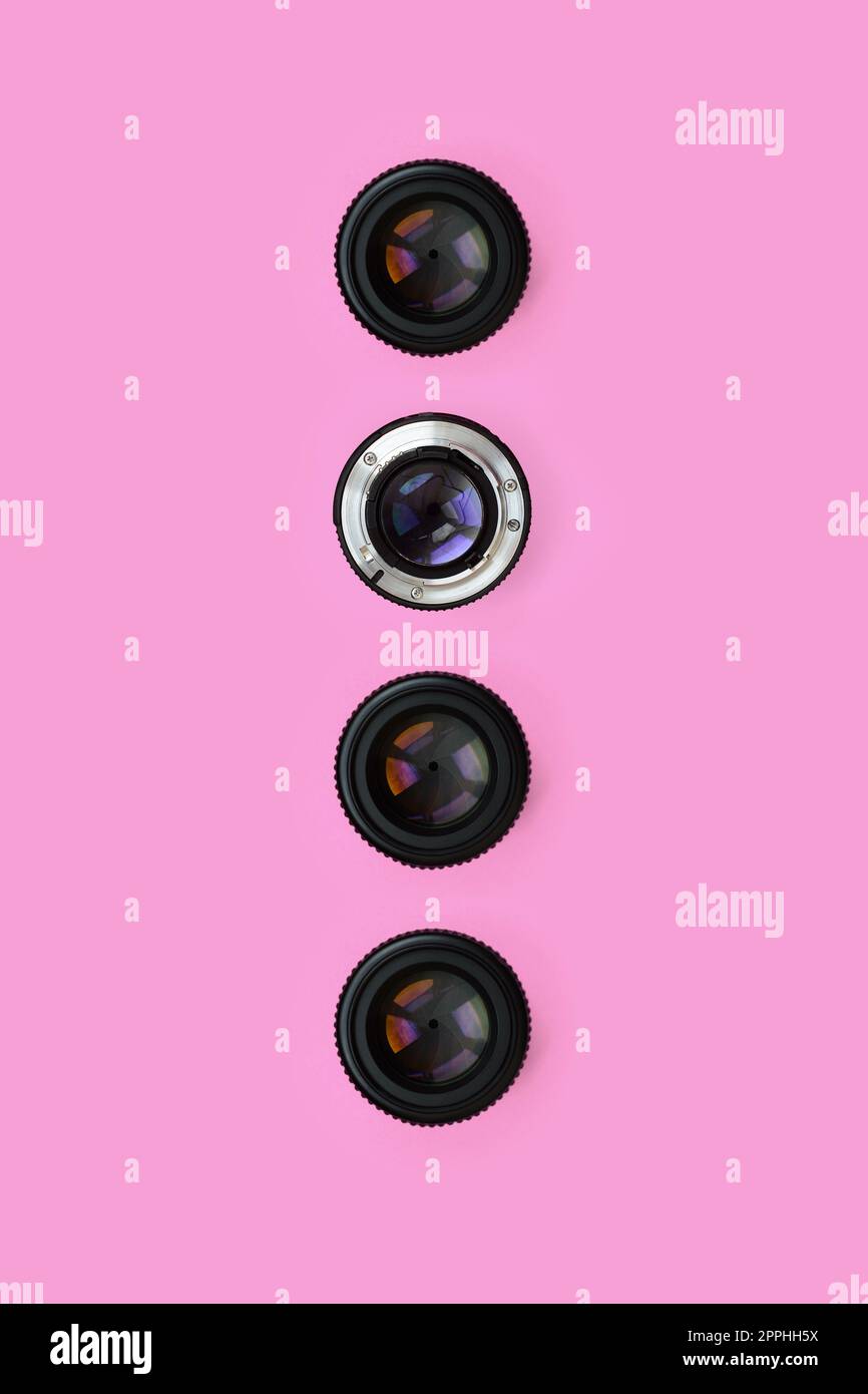 A few camera lenses with a closed aperture lie on texture background of fashion pastel pink color paper in minimal concept. Abstract trendy pattern Stock Photo