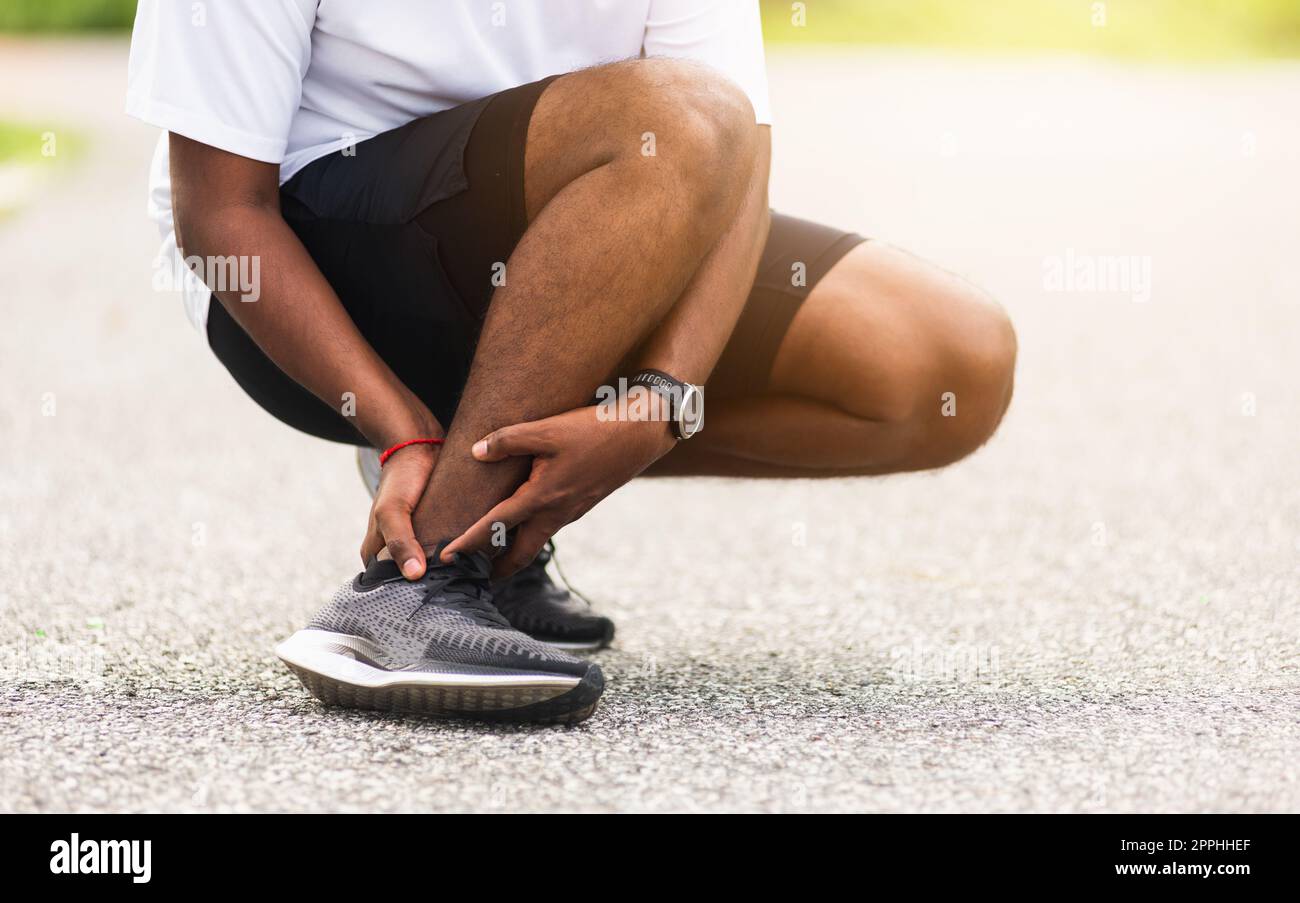 sport runner man use hands joint hold leg pain because of twisted ankle broken while running Stock Photo