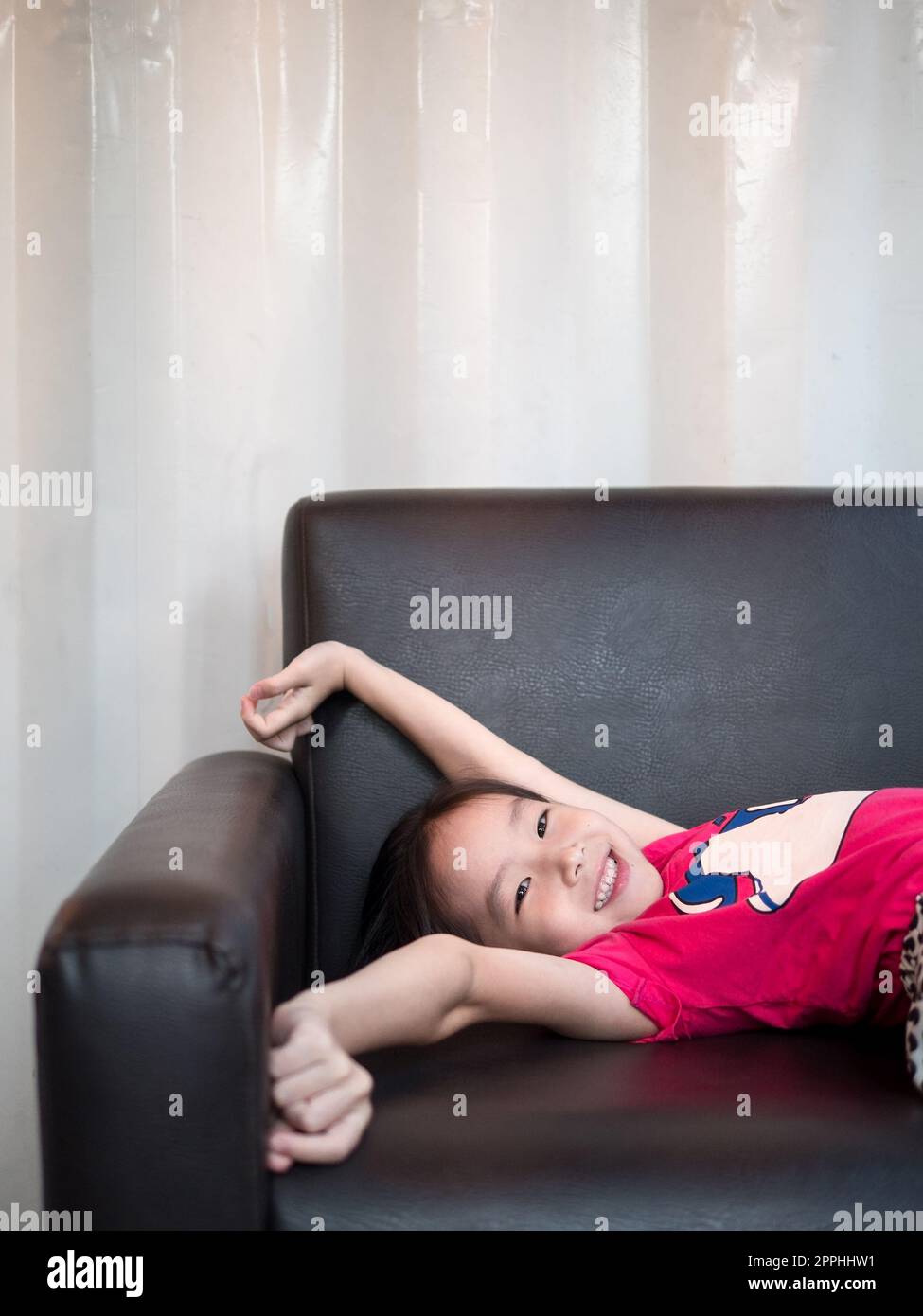 little asian child girl kid stretch oneself  on the sofa after her daytime sleepiness Stock Photo