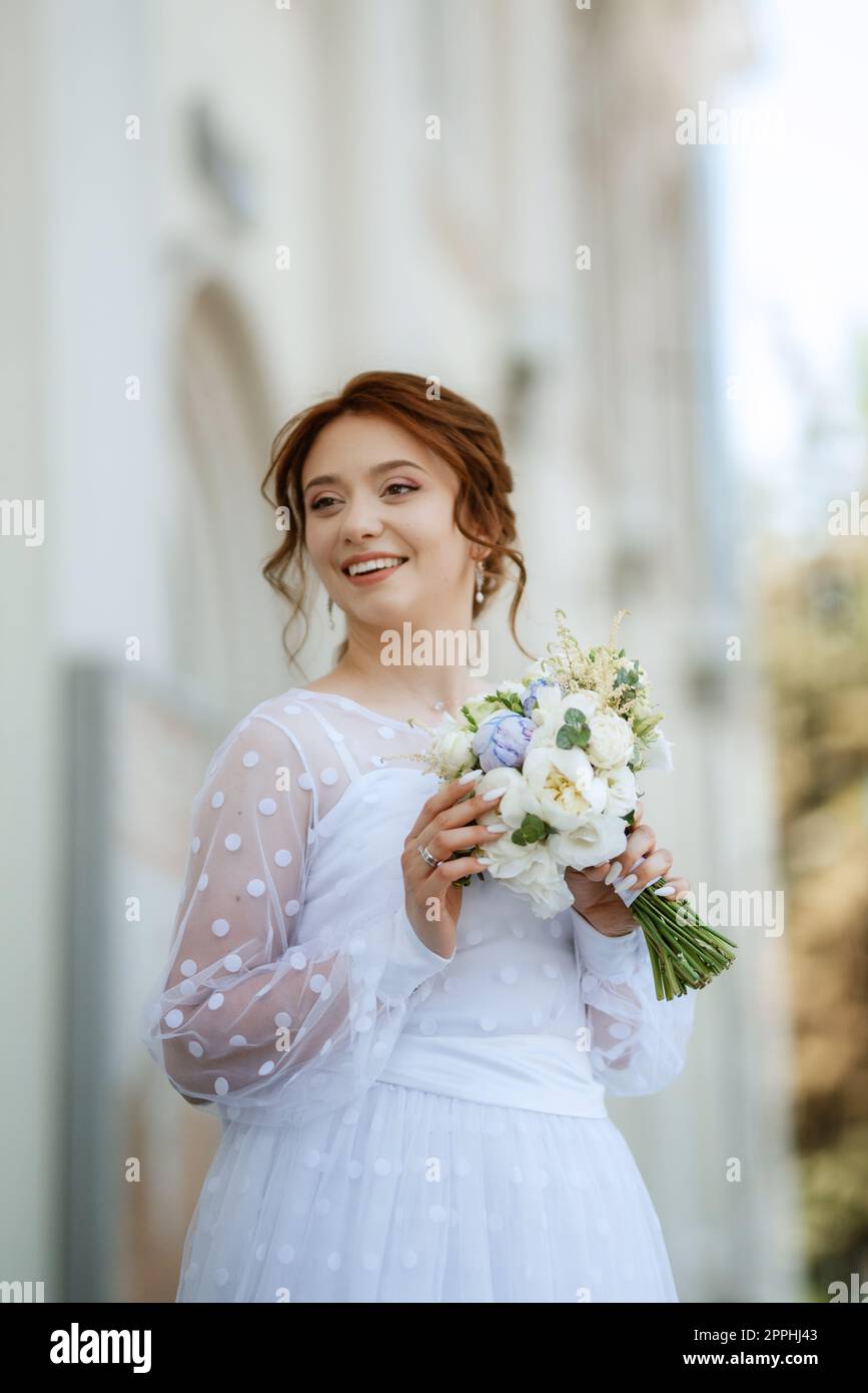portrait of a young bride girl in a light dress in an urban environment Stock Photo