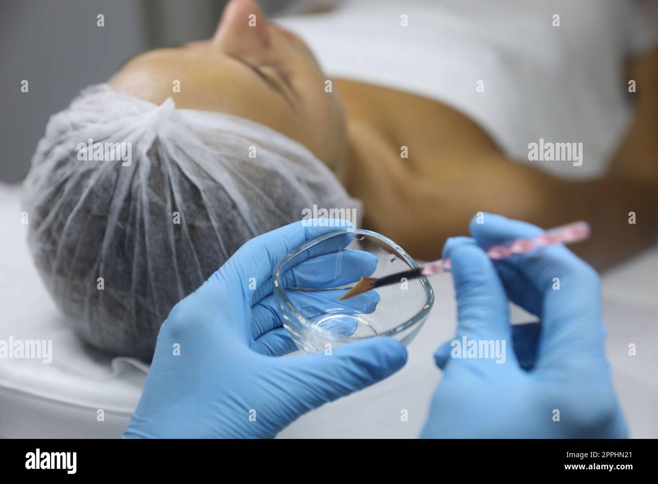 Cosmetologist with bowl and brush in salon. Peeling procedure Stock
