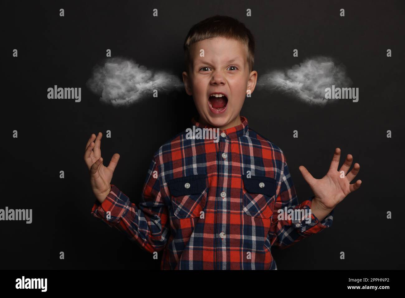 Aggressive little boy with steam coming out of his ears on black background Stock Photo