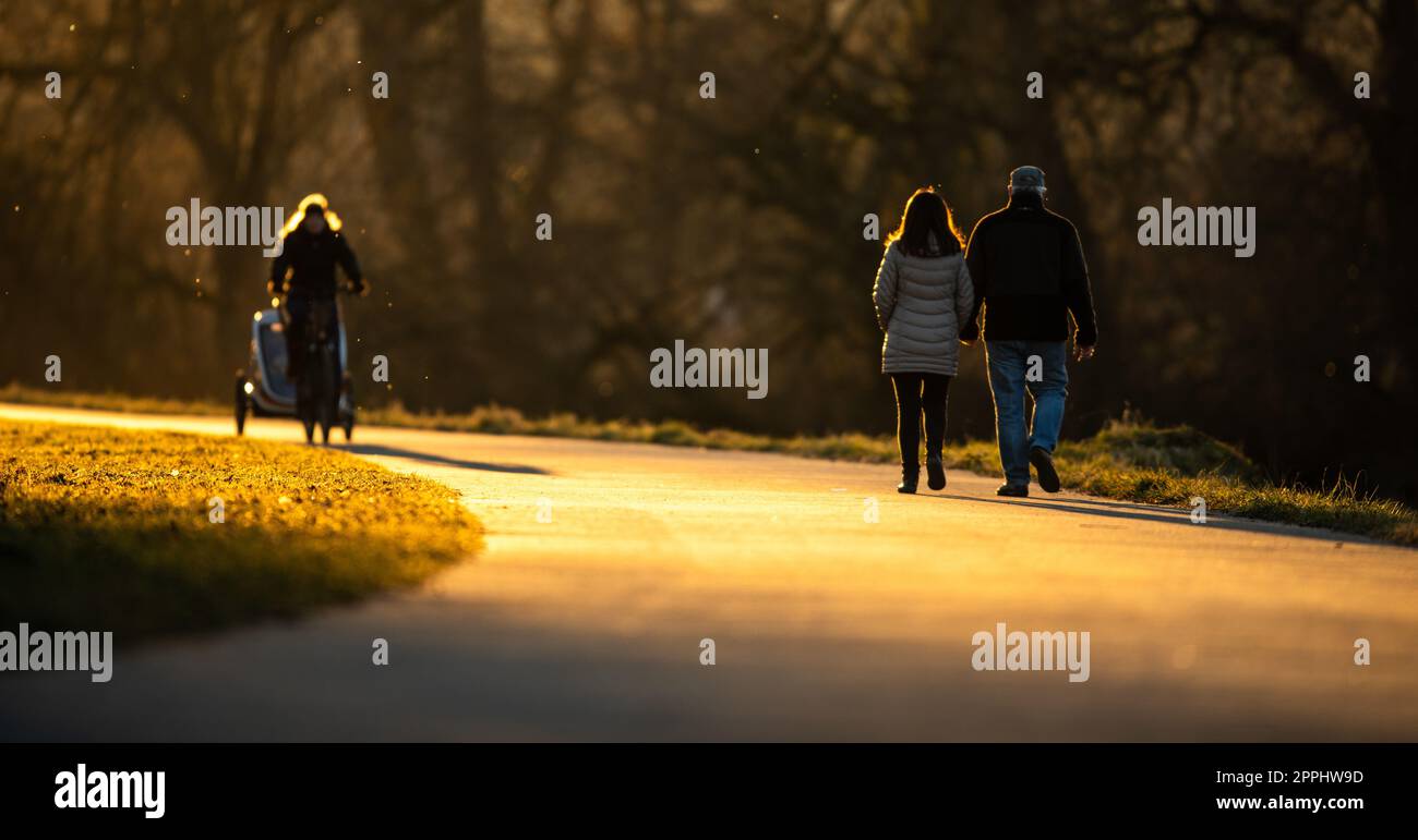 People walking along a river in a park on a lovely winter evening Stock Photo