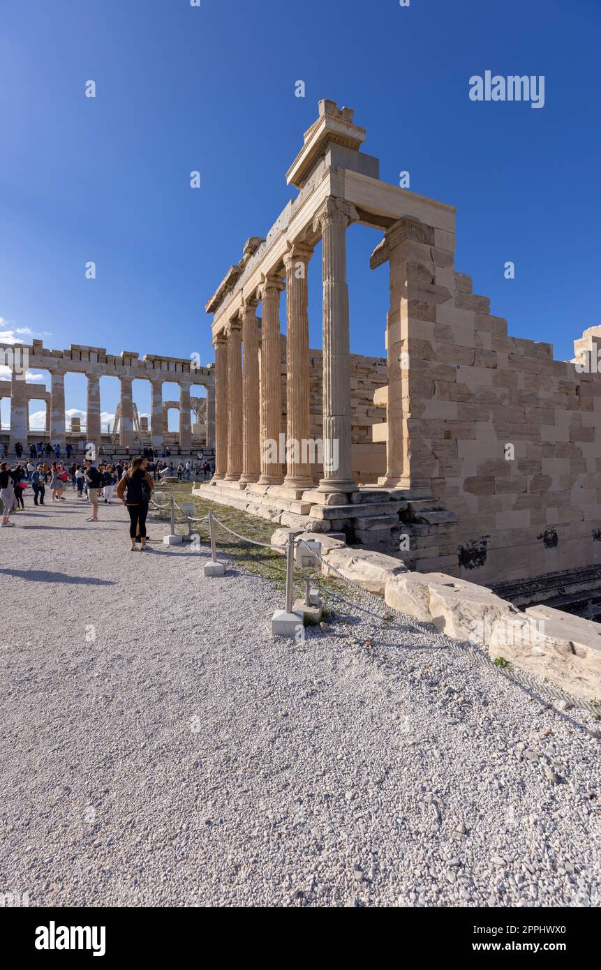 Athens, Greece - October 17, 2022: Group of tourists in front of  Erechtheion, Temple of Athena Polias on Acropolis of Athens. Parthenon in the distance Stock Photo