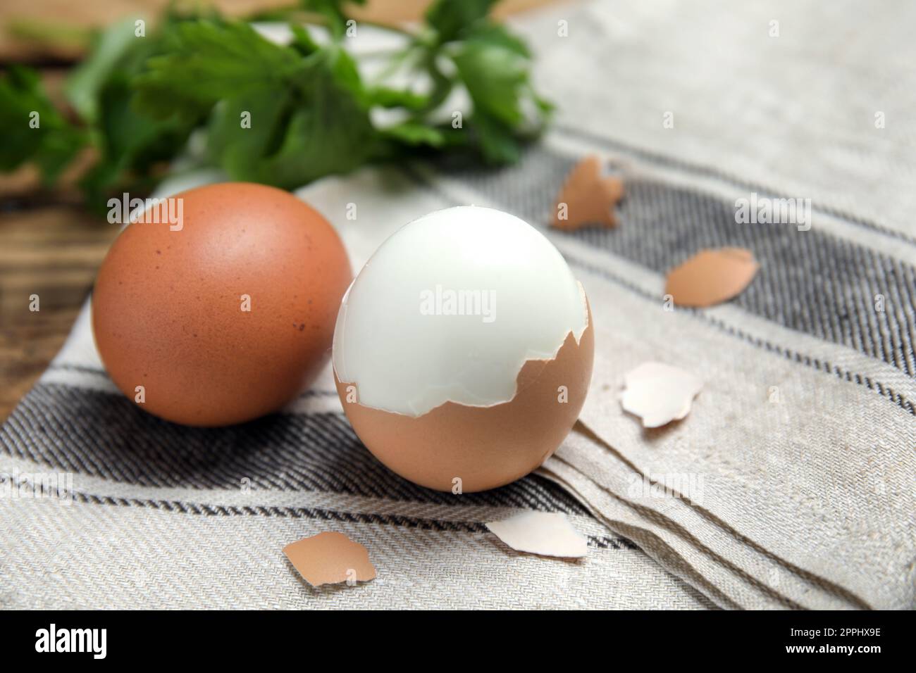 Boiled eggs and pieces of shell on kitchen towel, closeup Stock Photo