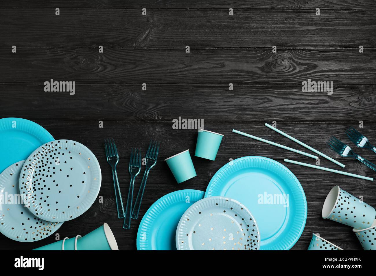 Disposable tableware on black wooden background, flat lay. Space for text Stock Photo