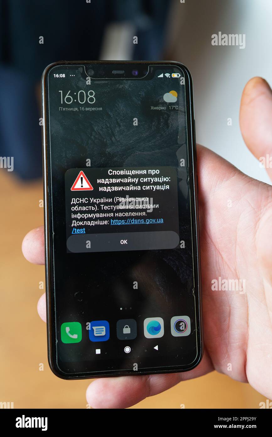 Rivne, Ukraine - September 16, 2022: Emergency notification from the State Emergency Service of Ukraine to smartphone. Girl hold mobile phone with alarm alert for Ukraine from DSNS during martial law. Stock Photo