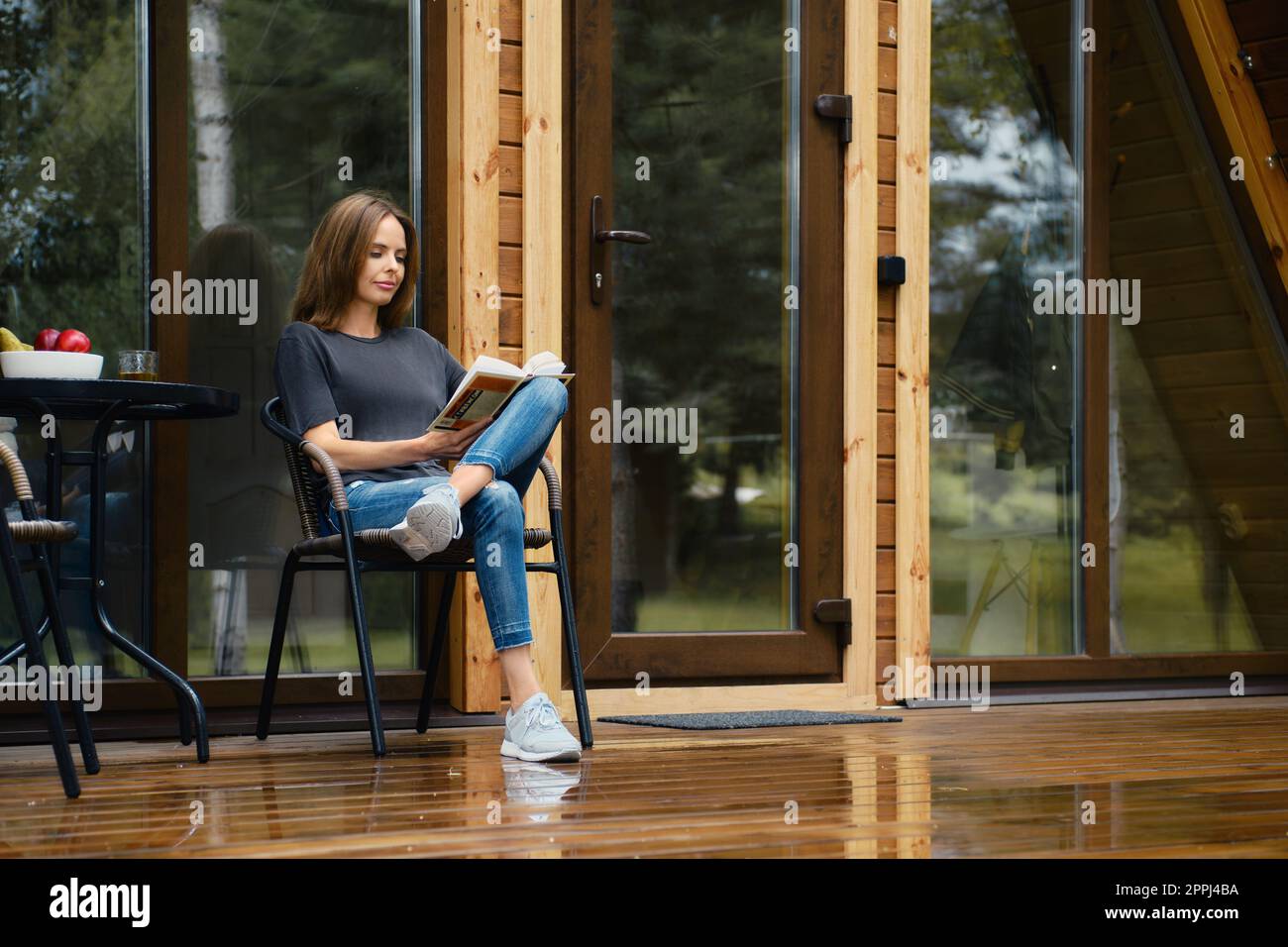 Cute woman sits on terrace and reads novel Stock Photo