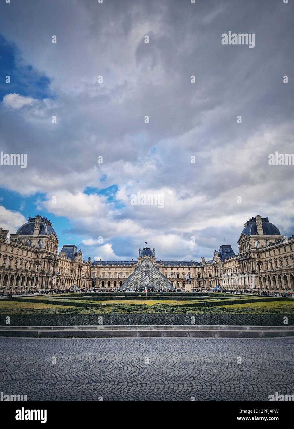 Outdoors view to the Louvre Museum in Paris, France. The historical palace building with the modern glass pyramid in center, vertical background Stock Photo