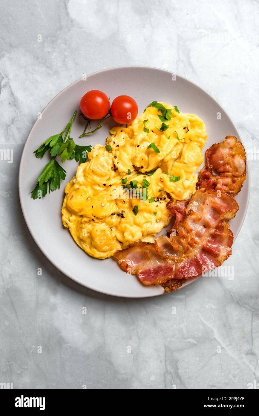Scrambled Eggs and Bacon for breakfast, top view, copy space. Keto food, healthy breakfast with scrambled egg. Stock Photo