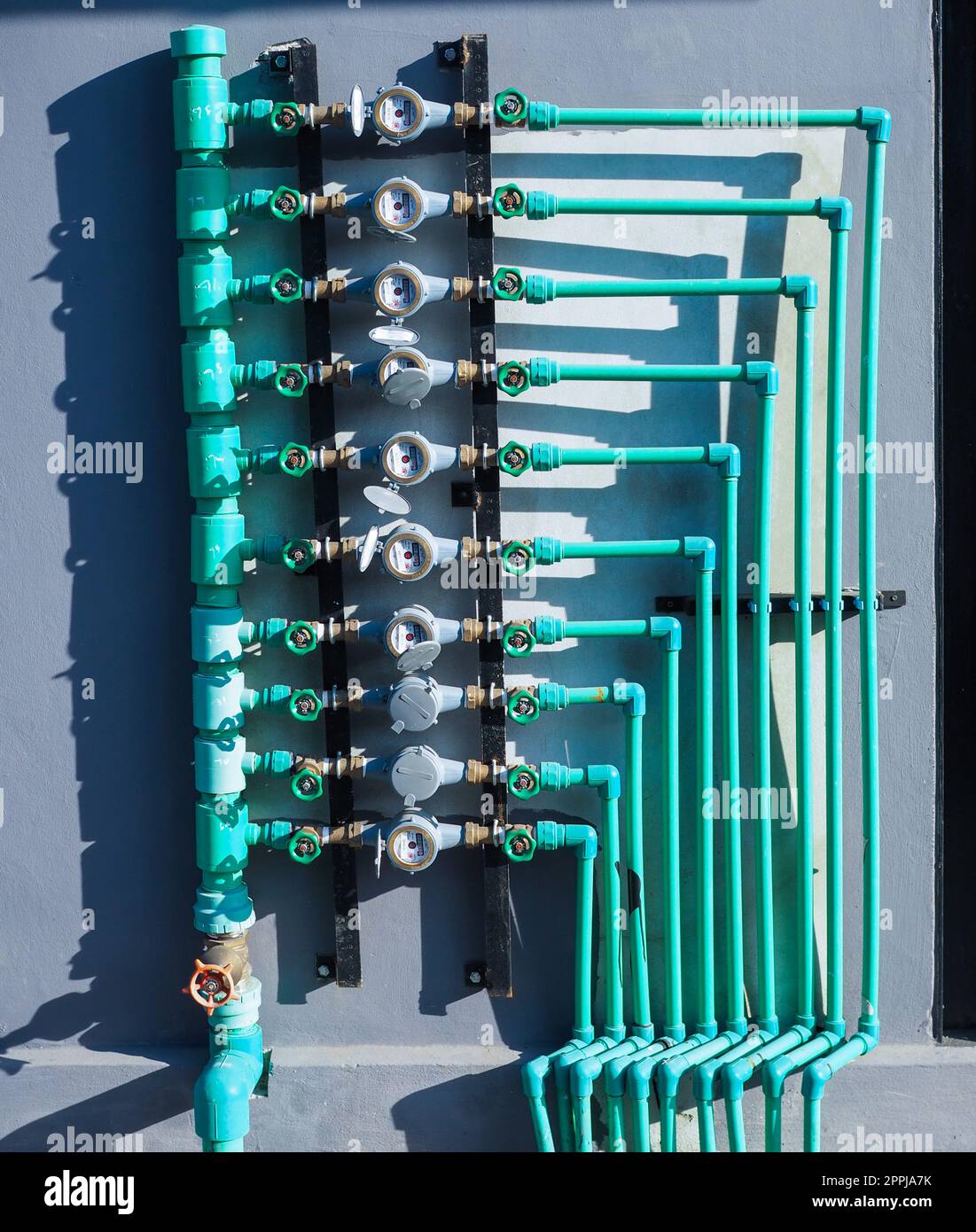 Water meter panels, water valves, and green water pipes arranged on the